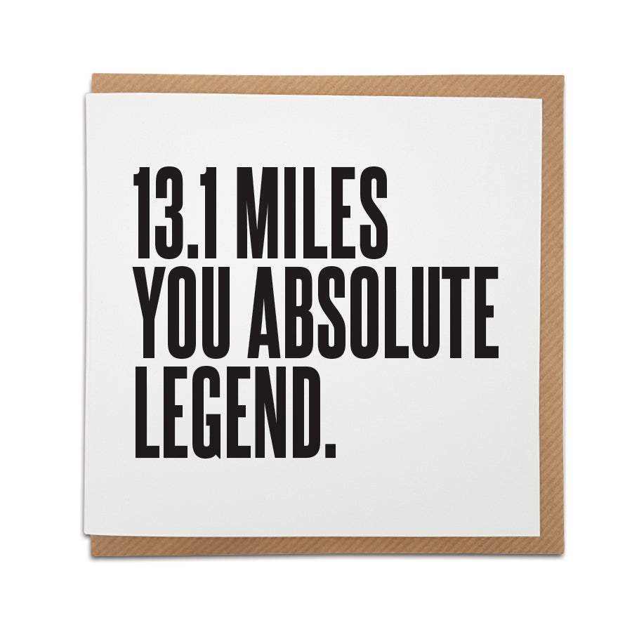 Square half marathon congratulations card resting on a brown kraft envelope. The design features bold black typography on a clean white background reading "13.1 MILES YOU ABSOLUTE LEGEND.". Half marathon runner greeting card designed by Local Lingo.