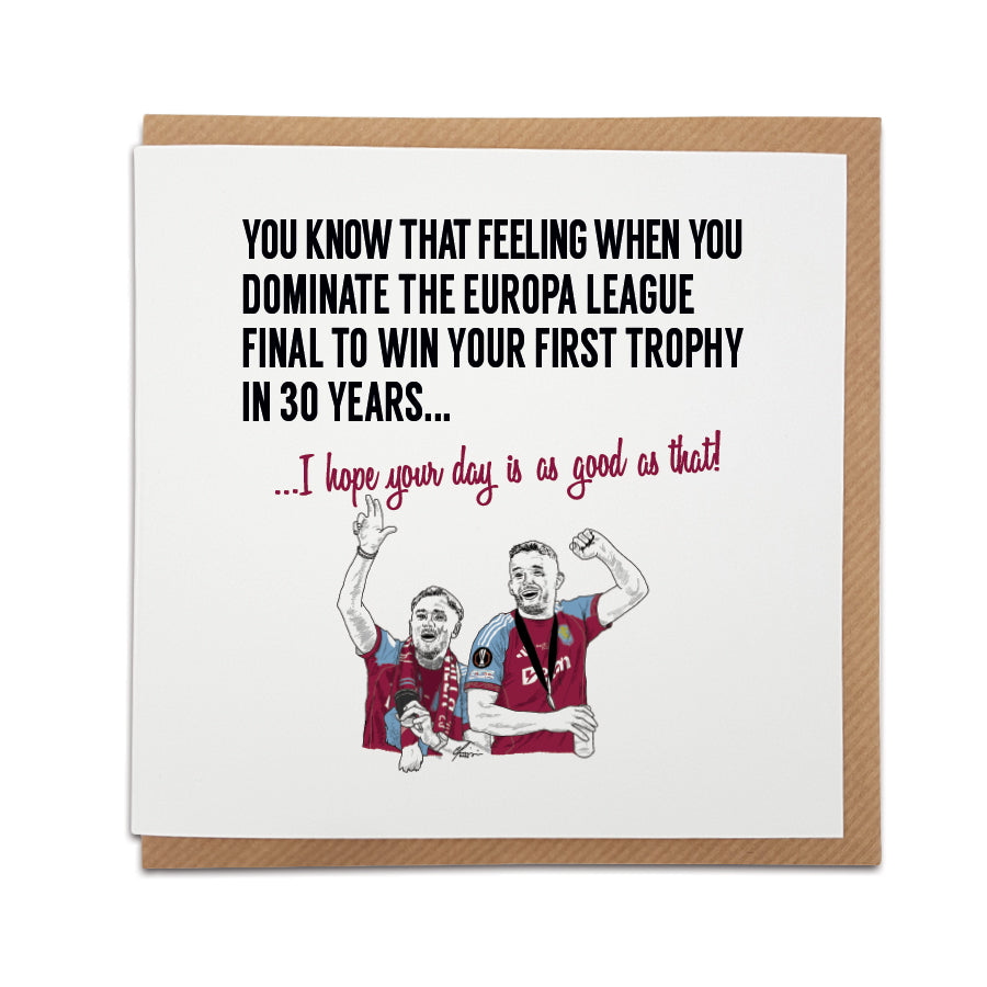 Square birthday greeting card resting on a brown kraft envelope. Bold black text reads "YOU KNOW THAT FEELING WHEN YOU DOMINATE THE EUROPA LEAGUE FINAL TO WIN YOUR FIRST TROPHY IN 30 YEARS..." followed by claret red text reading "...I hope your day is as good as that!". Below is a hand drawn illustration of Aston Villa players Matty Cash and John McGinn passionately celebrating in their claret and blue kits. Aston 