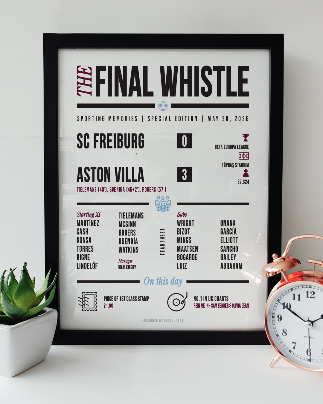 A framed 'Final Whistle' football keepsake print celebrating Aston Villa's historic 3-0 UEFA Europa League Final victory over SC Freiburg. The print features the match stats, starting lineup, and "On this day" trivia in claret and blue text. It is displayed on a white surface next to a small green potted plant and a classic copper alarm clock. Modern football memorabilia designed by Local Lingo.