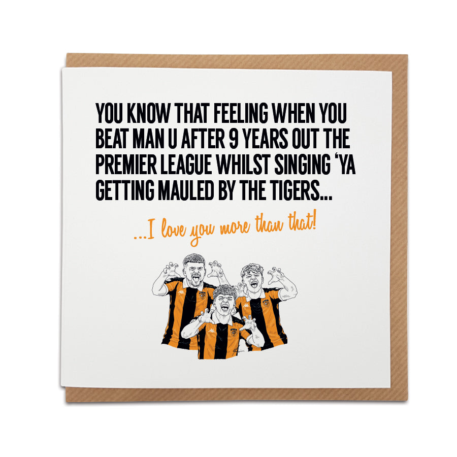 Square greeting card resting on a brown kraft envelope. Bold black text reads "YOU KNOW THAT FEELING WHEN YOU BEAT MAN U AFTER 9 YEARS OUT THE PREMIER LEAGUE WHILST SINGING 'YA GETTING MAULED BY THE TIGERS..." followed by orange cursive text reading "...I love you more than that!". Below is a hand-drawn illustration of three Hull City fans in amber and black home shirts performing a tiger claw gesture.