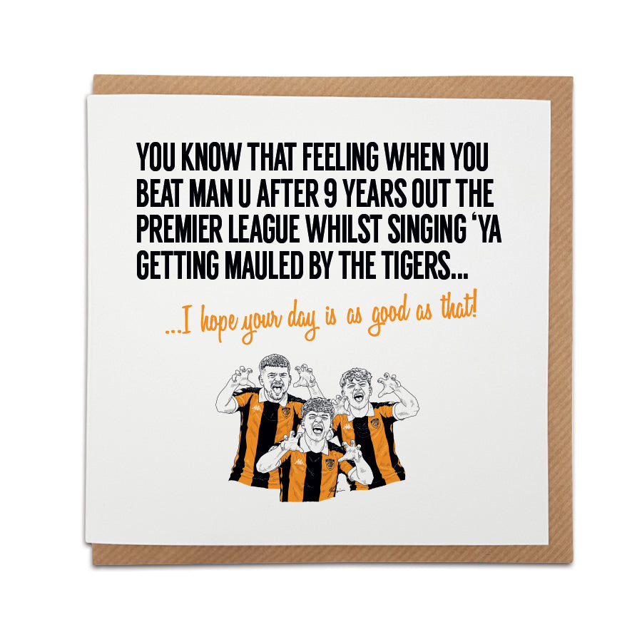 Square greeting card resting on a brown kraft envelope. Bold black text reads "YOU KNOW THAT FEELING WHEN YOU BEAT MAN U AFTER 9 YEARS OUT THE PREMIER LEAGUE WHILST SINGING 'YA GETTING MAULED BY THE TIGERS..." followed by orange cursive text reading "...I hope your day is as good as that!". Below is a hand-drawn illustration of three Hull City fans in amber and black home shirts performing a tiger claw gesture.